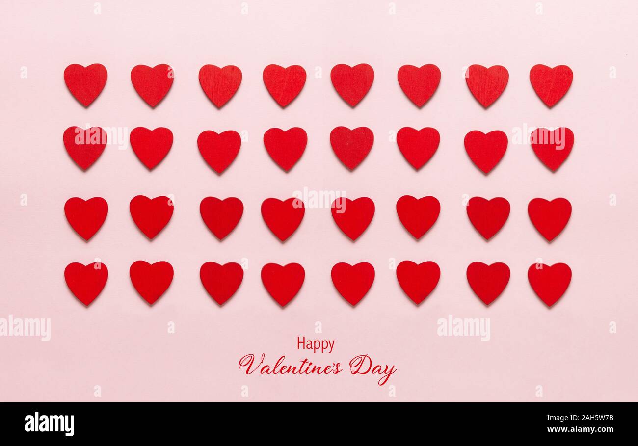 Red cuori di legno sul rosa pastello sfondo. Sfondo astratto con legno tagliare le forme. Valentino, biglietti di auguri, invito celebrazione concep Foto Stock