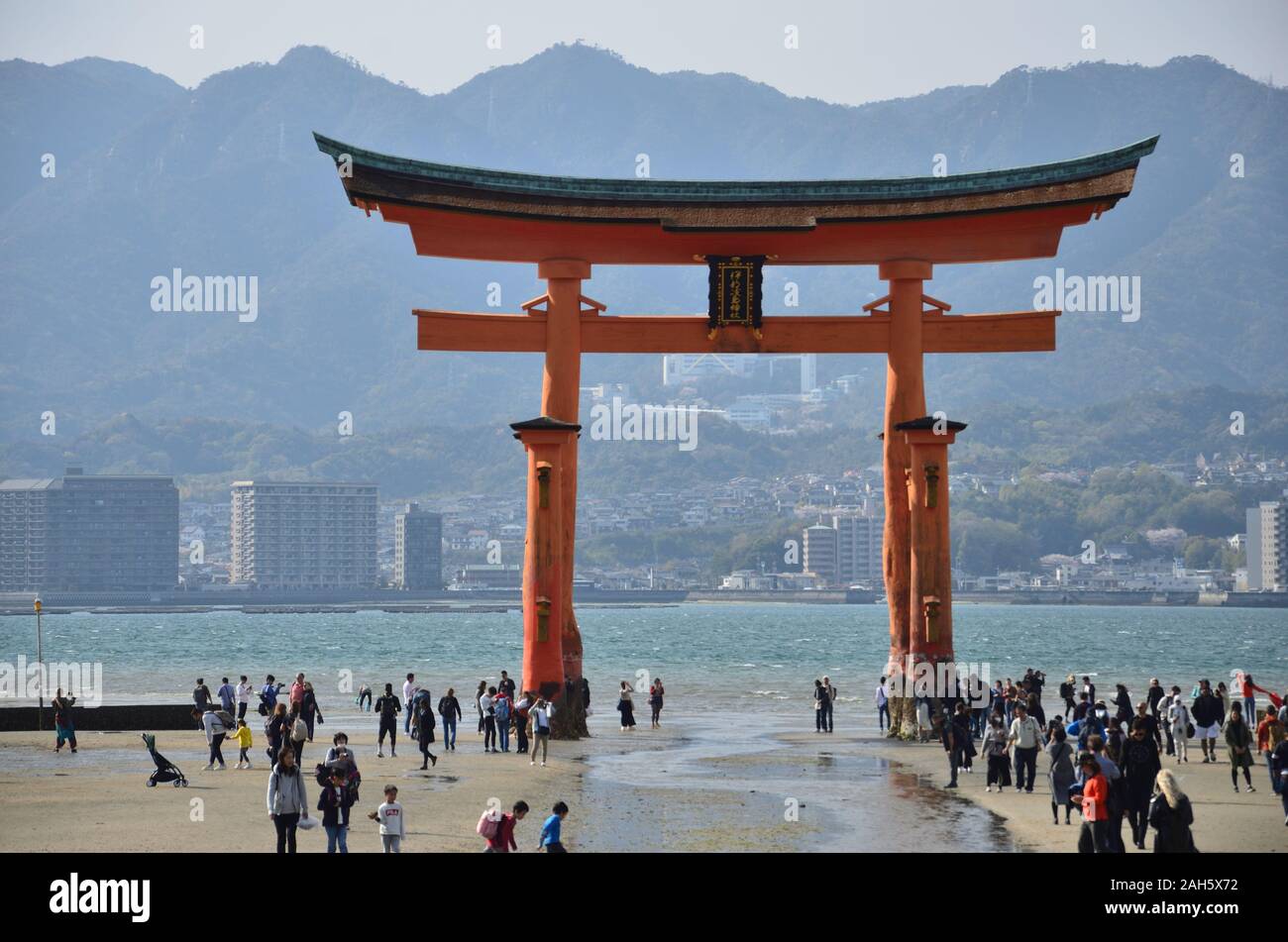 Molte persone ai piedi della grande Torii sull'isola di Miyajima Foto Stock