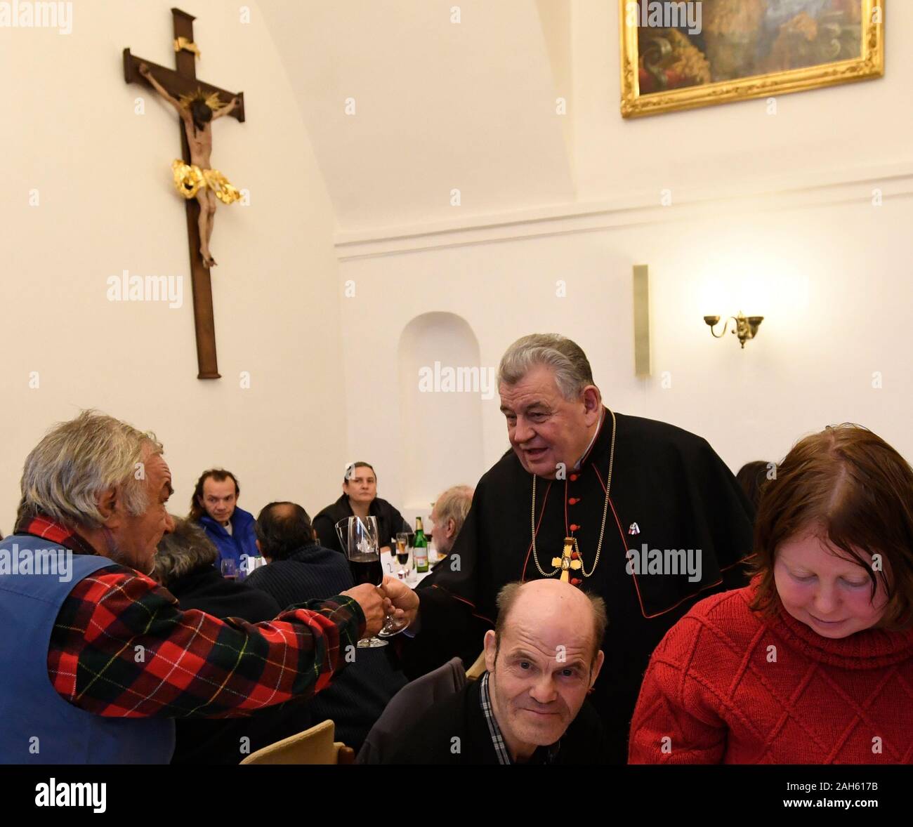 Praga, Repubblica Ceca. 25 Dic, 2019. Alcuni 300 persone povere, alcuni di loro senza fissa dimora o in una diversa vita difficile situazione ha avuto una cena su invito del cristiano di Sant'Egidio il movimento in Arcivescovado di Praga Palace, nella Repubblica ceca il 25 dicembre 2019. Arcivescovo di Praga Il Cardinale Dominik Duka, up-centro, in persona ha salutato ciascuno degli ospiti e aveva un brindisi con loro nel suo palazzo. Credito: Michal Krumphanzl/CTK foto/Alamy Live News Foto Stock