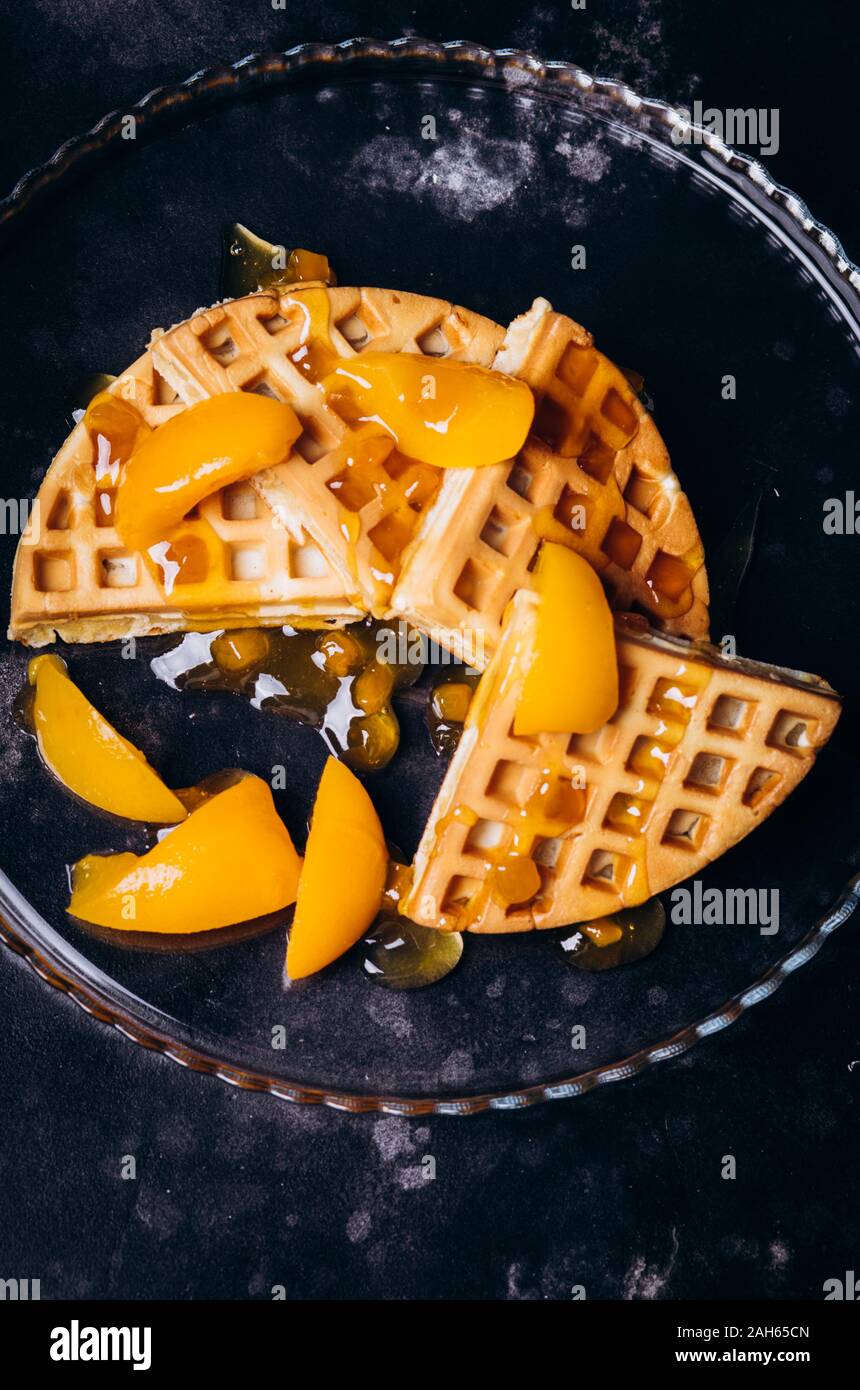 Cialde con pesche per la colazione su uno sfondo nero. Foto Stock