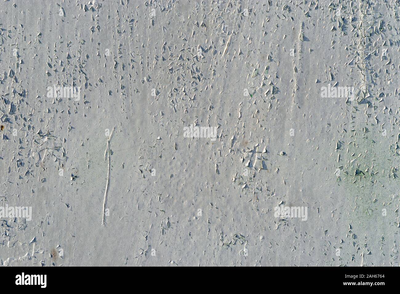 Vecchio bianco metallo superficie verniciata con vernice di pelatura, graffi e crepe in condizioni di luce solare intensa. Luce di diversi punti verdi sono visibili. Abstract bianco - g Foto Stock