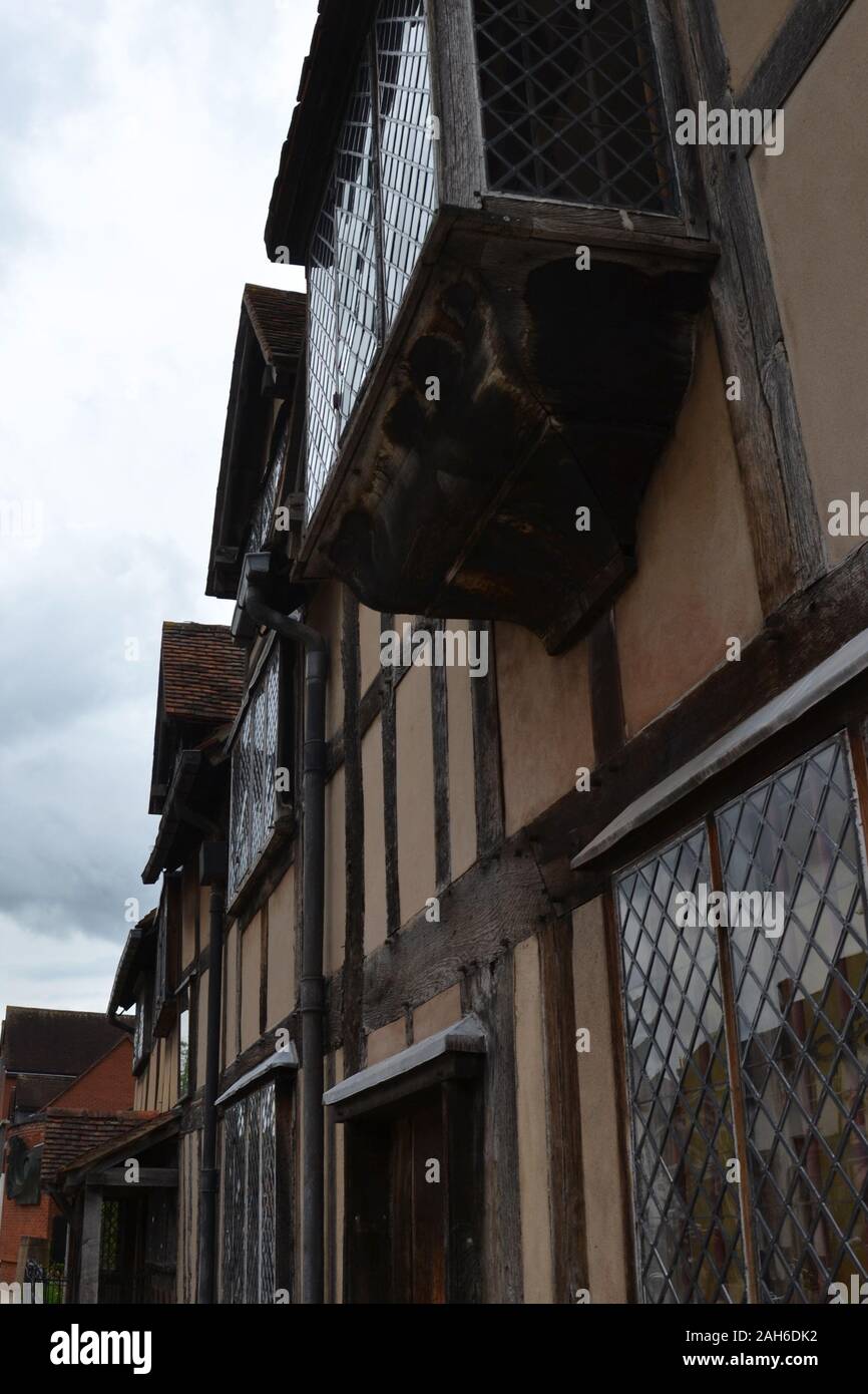 Finestre a Baia, vetro retinato, pareti gialle e legno incorniciata edificio contro il cielo grigio. Inglese tradizionale edificio Tudor: William Shakespeare' Foto Stock