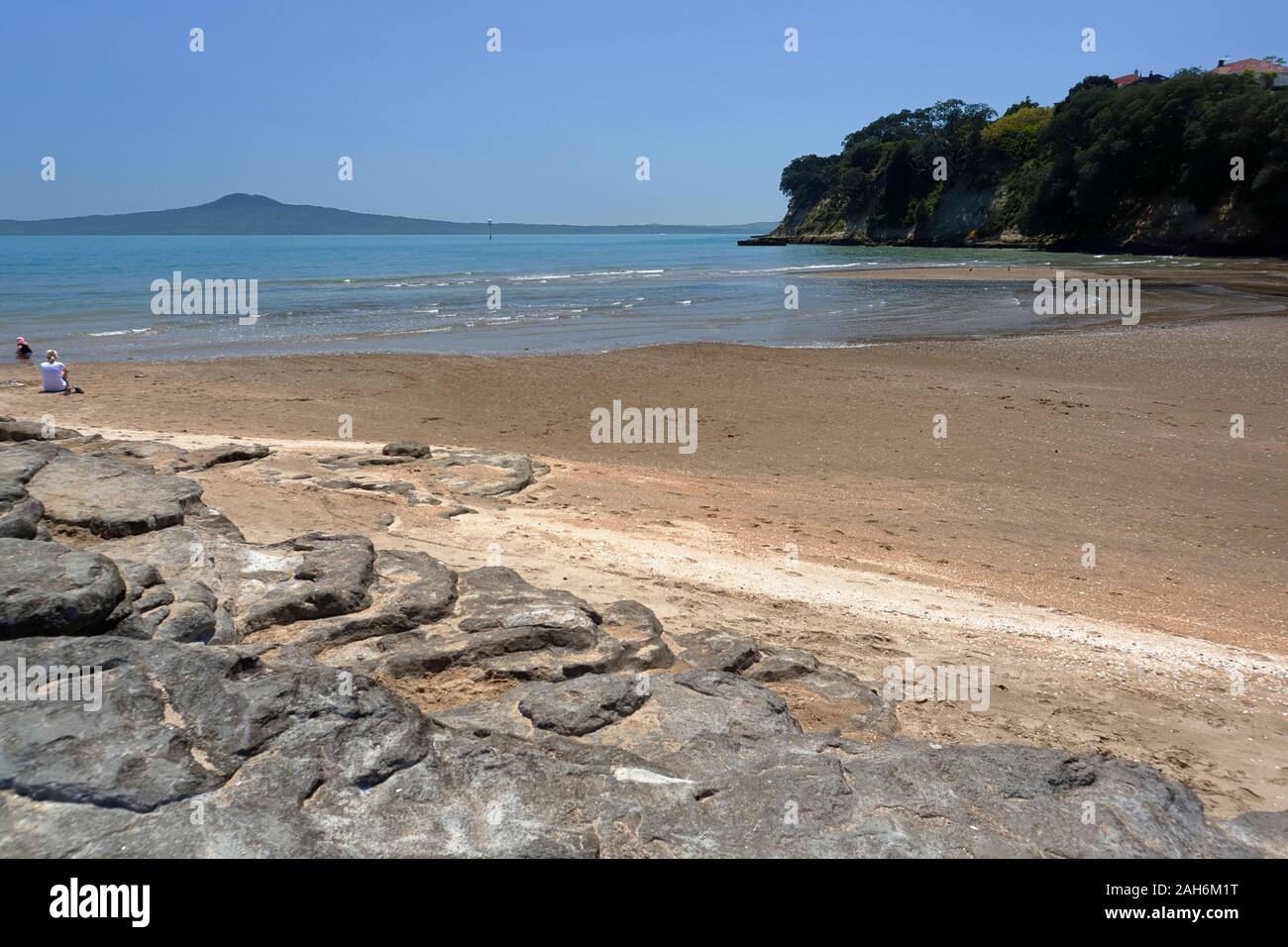 Con Rangitoto isola nella distanza di una madre e bambino godere il mare e la sabbia a San Heliers Beach, Auckland, Nuova Zelanda Foto Stock