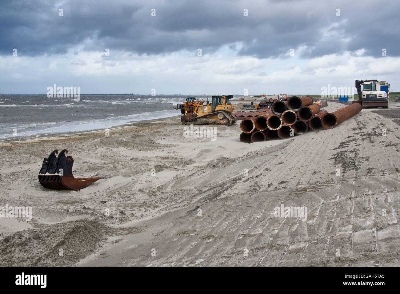 Rinforzo Dyke, bulldozer spinge spruzzata sabbia in mare per evitare il pericolo di allagamento Foto Stock