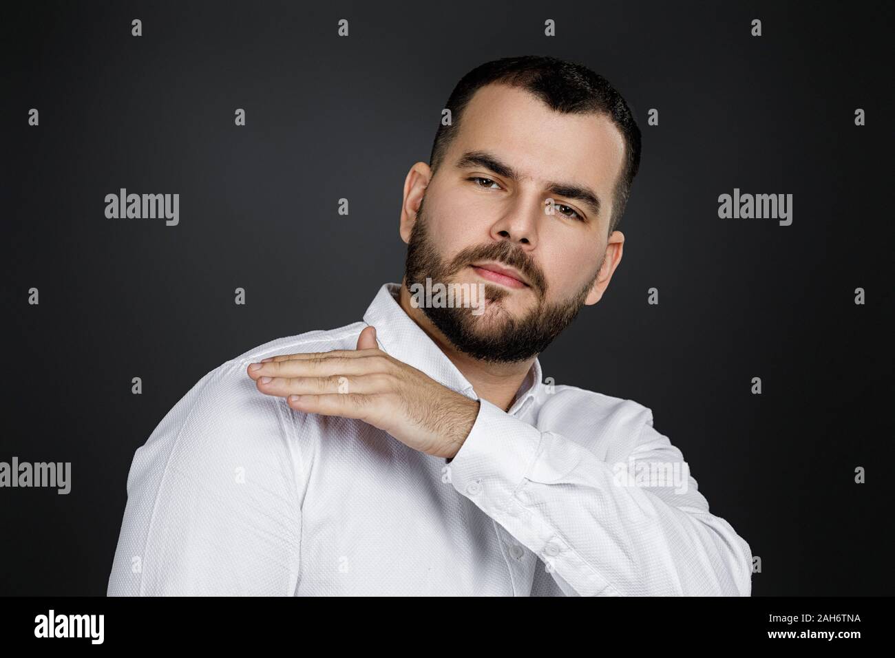 Uomo Barbuto in camicia spazzola parapolvere spalla su sfondo nero. Tutto deve essere perfetto. Foto Stock