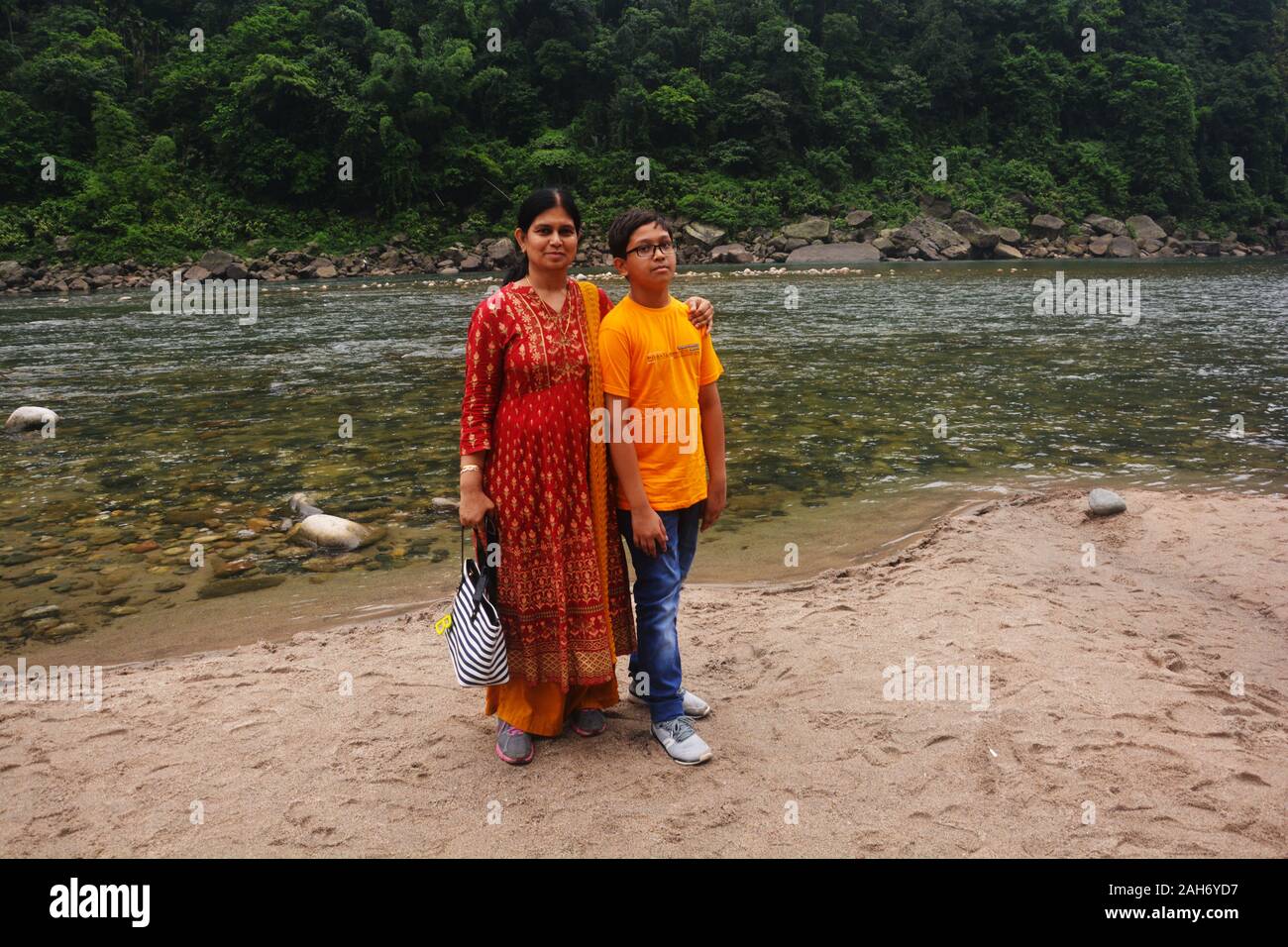 Close up di un turista, madre e figlio che posano per una foto sulle rive del fiume Umngot in Dawki, Meghalaya fluente verso Sylhet, messa a fuoco selettiva Foto Stock