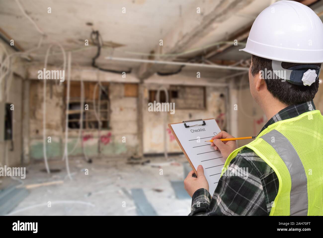 Una mezza età lavoratori asiatici controllare qualcosa con una lista di controllo nella sua mano. Foto Stock