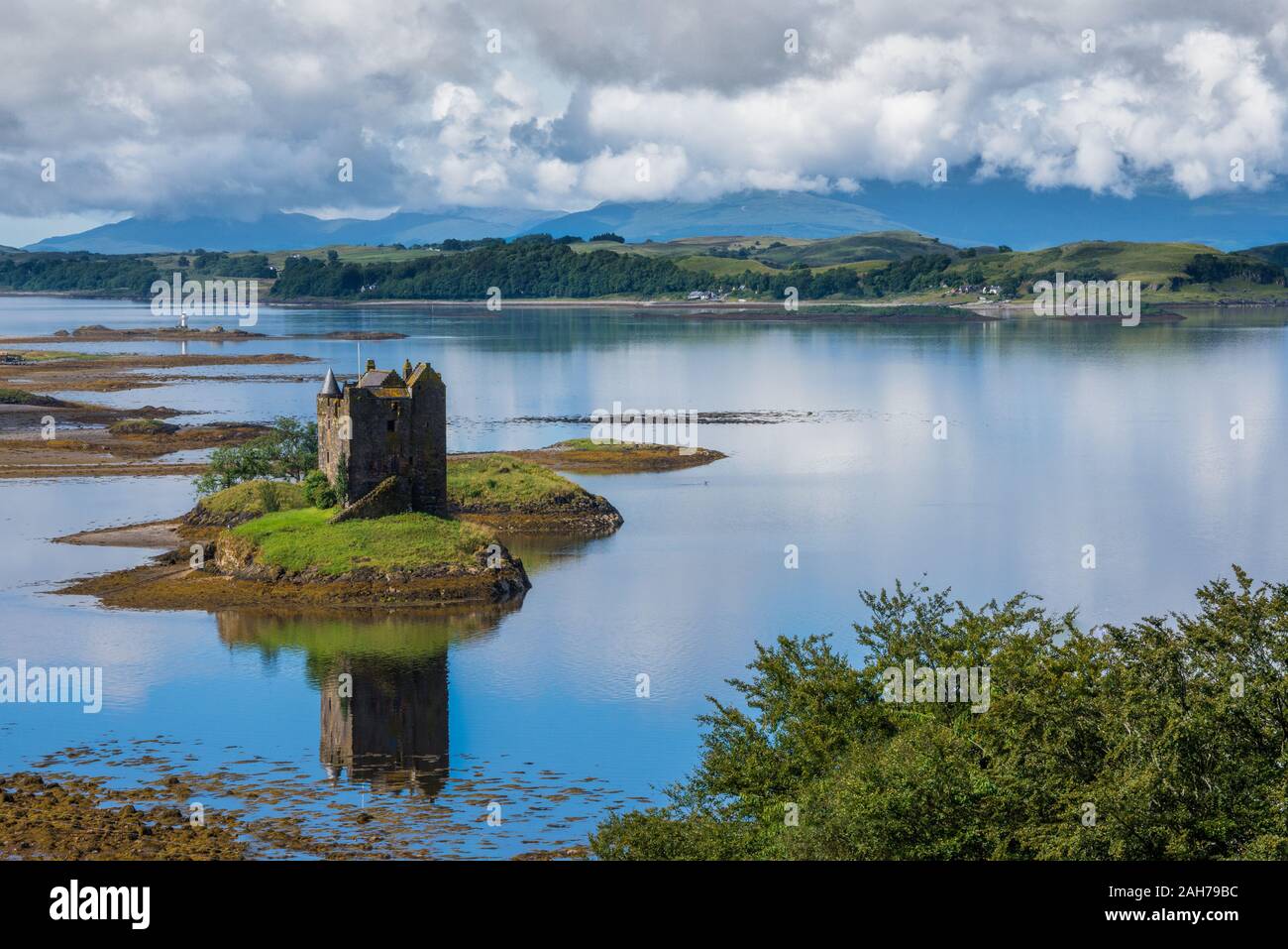 Un lago scozzese con un antico castello in piedi su un piccola isola e che riflette sull'acqua Foto Stock