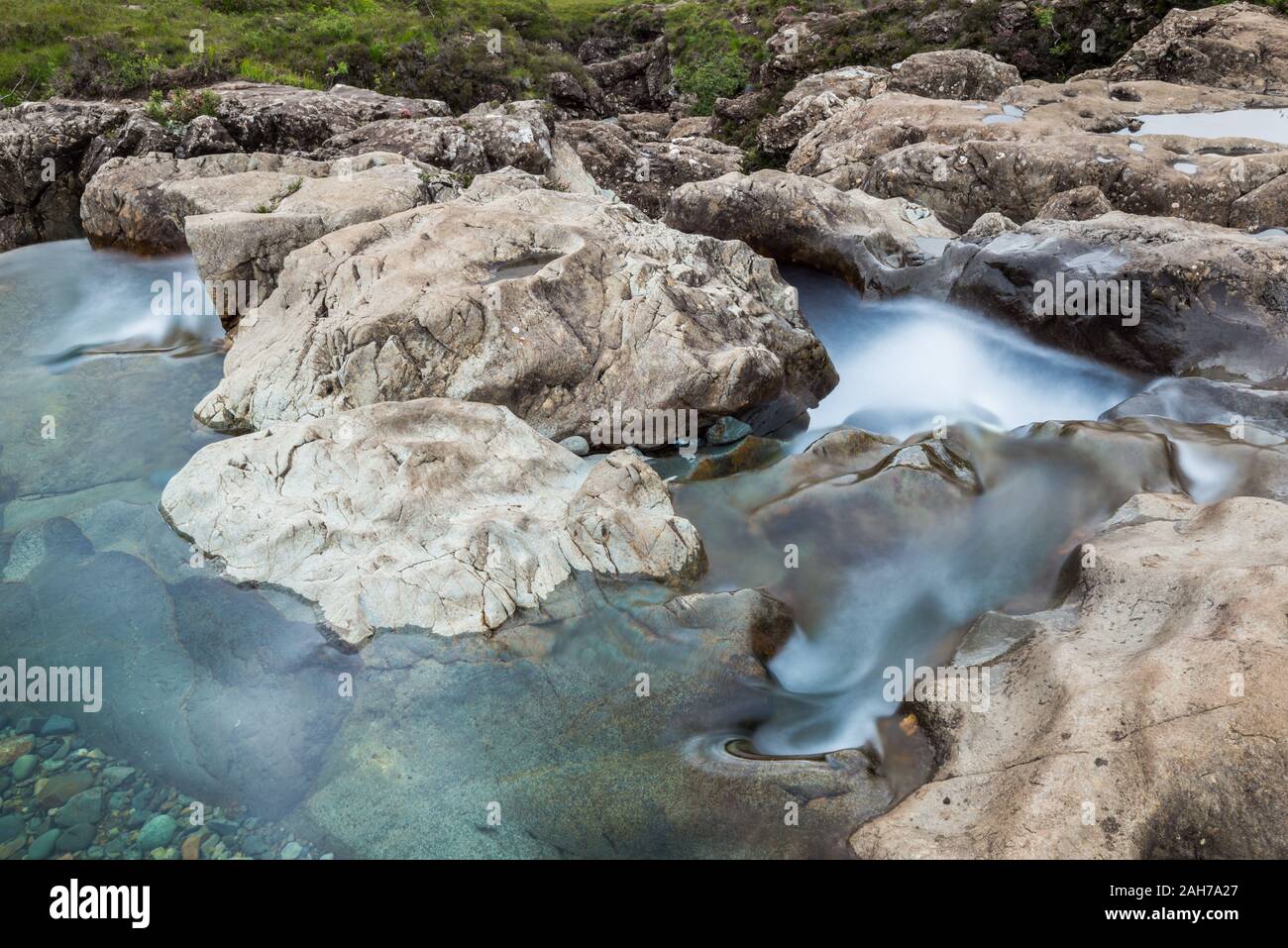 Le piscine Fairy rapide che corrono tra rocce bianche e verdi erba Foto Stock