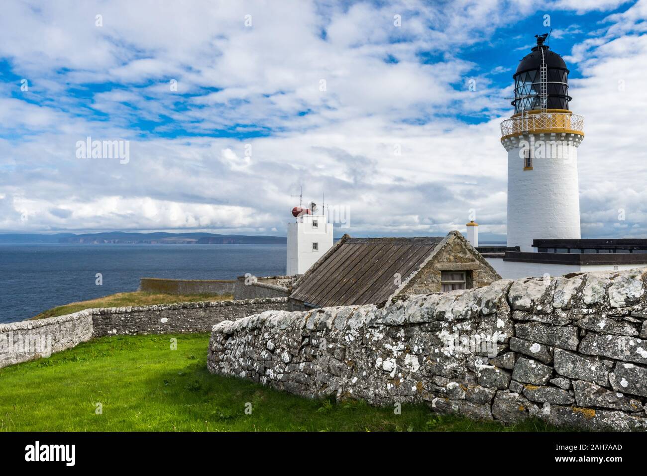 Il Dunnet Head Light si affaccia sul mare, circondato da un basso muro a secco Foto Stock