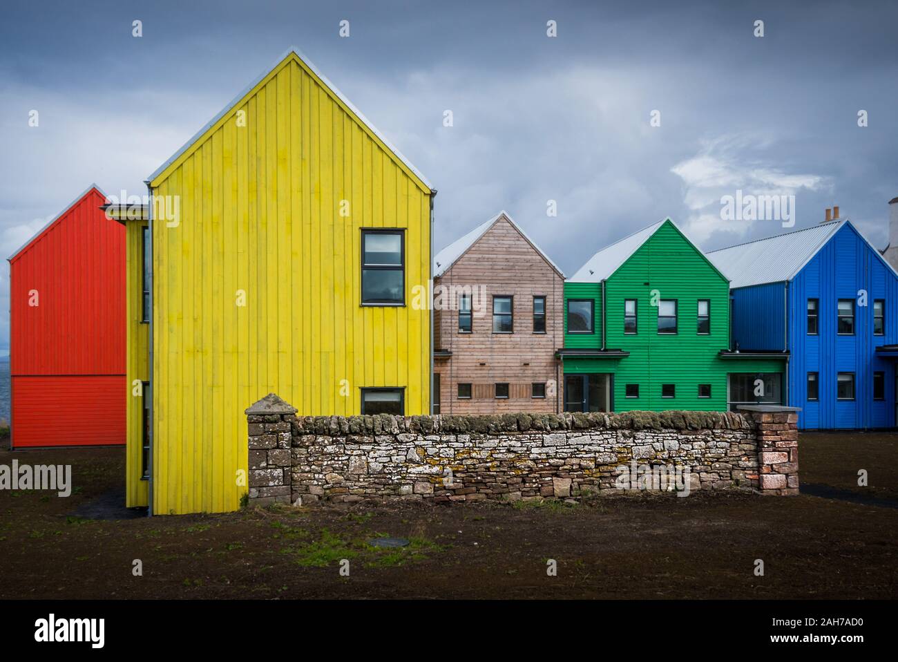 Una fila di colorate case di legno nel nord della Scozia sotto un cielo nuvoloso Foto Stock