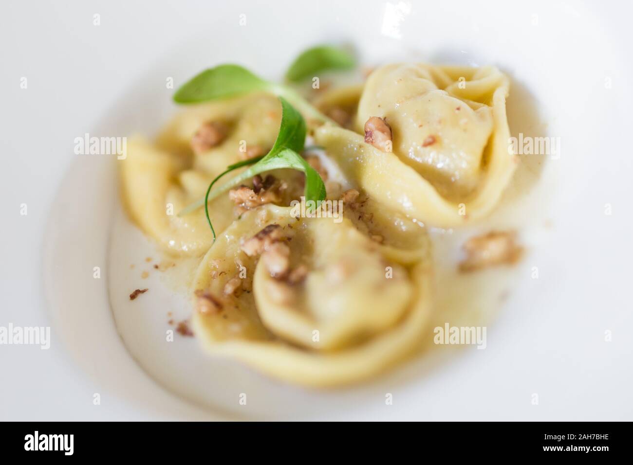 Primo piano di un piatto che cotta tre tortellini con un condimento di castagne e insalate Foto Stock