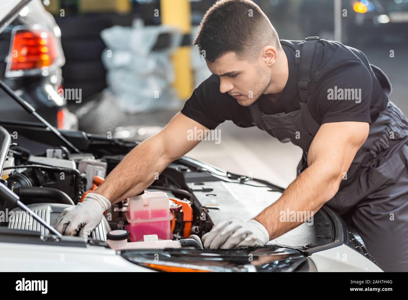 Giovanissimo meccanico auto ispezione vano motore in officina Foto Stock