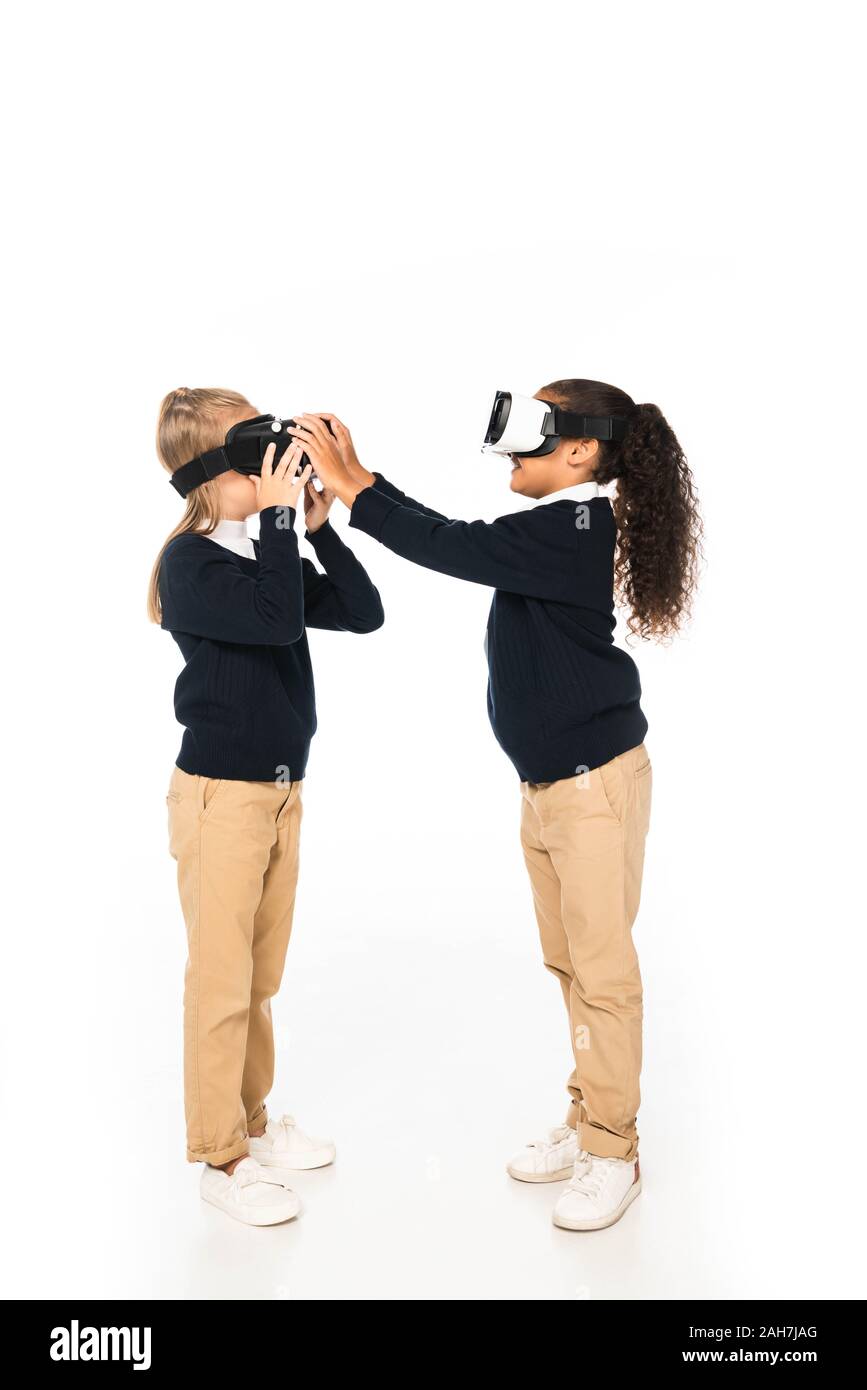 Lunghezza piena vista di due amici multiculturale utilizzando la realtà virtuale auricolari su sfondo bianco Foto Stock
