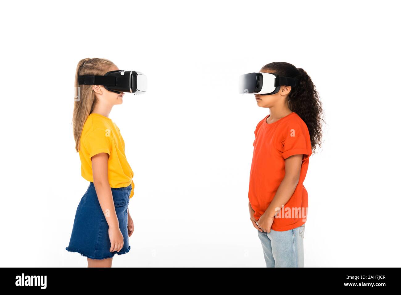 Due amici multiculturale guardando ogni altro mentre utilizzando la realtà virtuale auricolari isolato su bianco Foto Stock