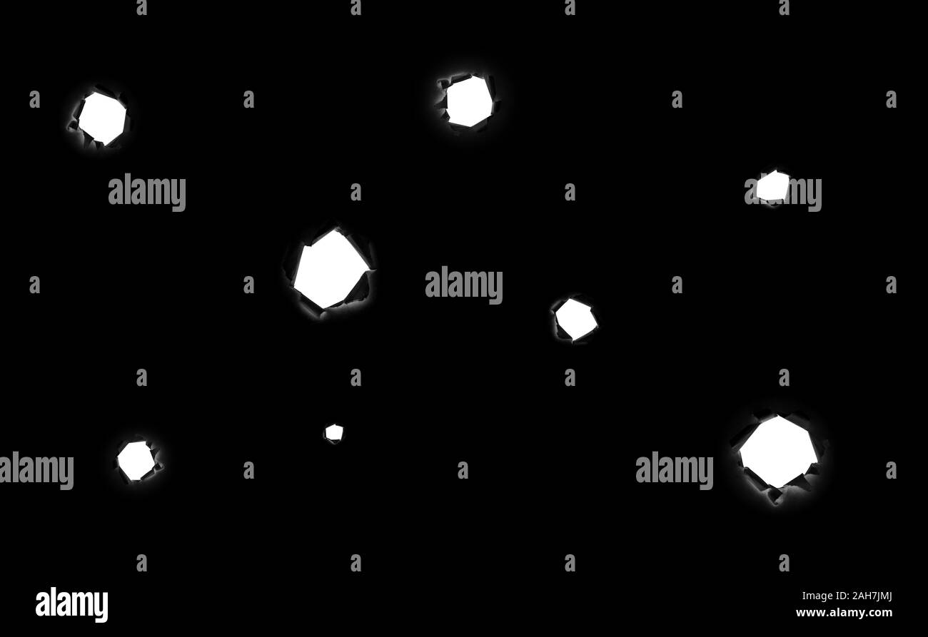 Un sacco di strappata fori circolari di dimensioni differenti in carta nera come se da proiettili con uno sfondo bianco all'interno isolato su uno sfondo nero. Bullet h Foto Stock