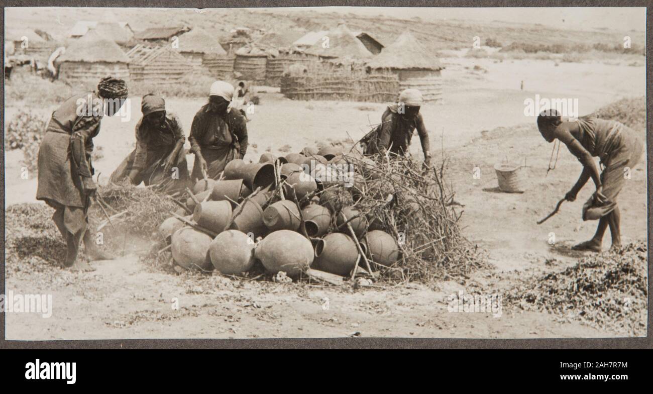 Somalia, un gruppo di lavoratori costruire un fuoco intorno appena gettato pentole. Parte di una serie che mostra il processo di creazione e di pentole di cottura, circa 1940. 2000/084/1/1/3/63. Foto Stock