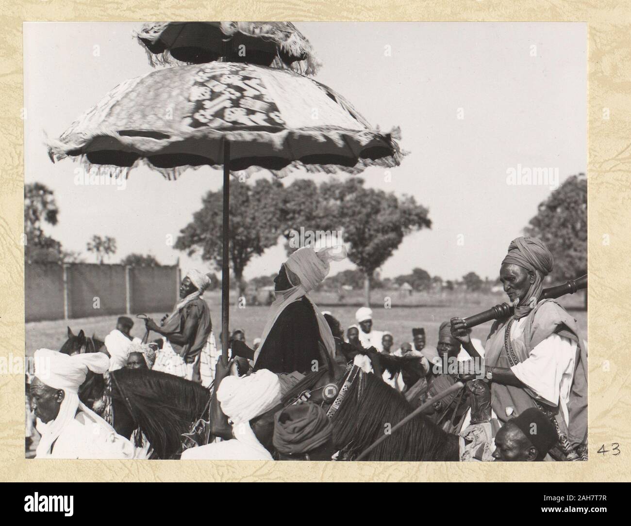 La Nigeria, il movimento del cerimoniale ombrello può essere visto in questa foto come essa viene ruotata. La didascalia recita: 'Tutti i governanti viaggiano sotto MULTI-ombrelloni colorati. L'ombrello viene continuamente ruotato da un servo", 1960. 2005/010/1/7/43. Foto Stock