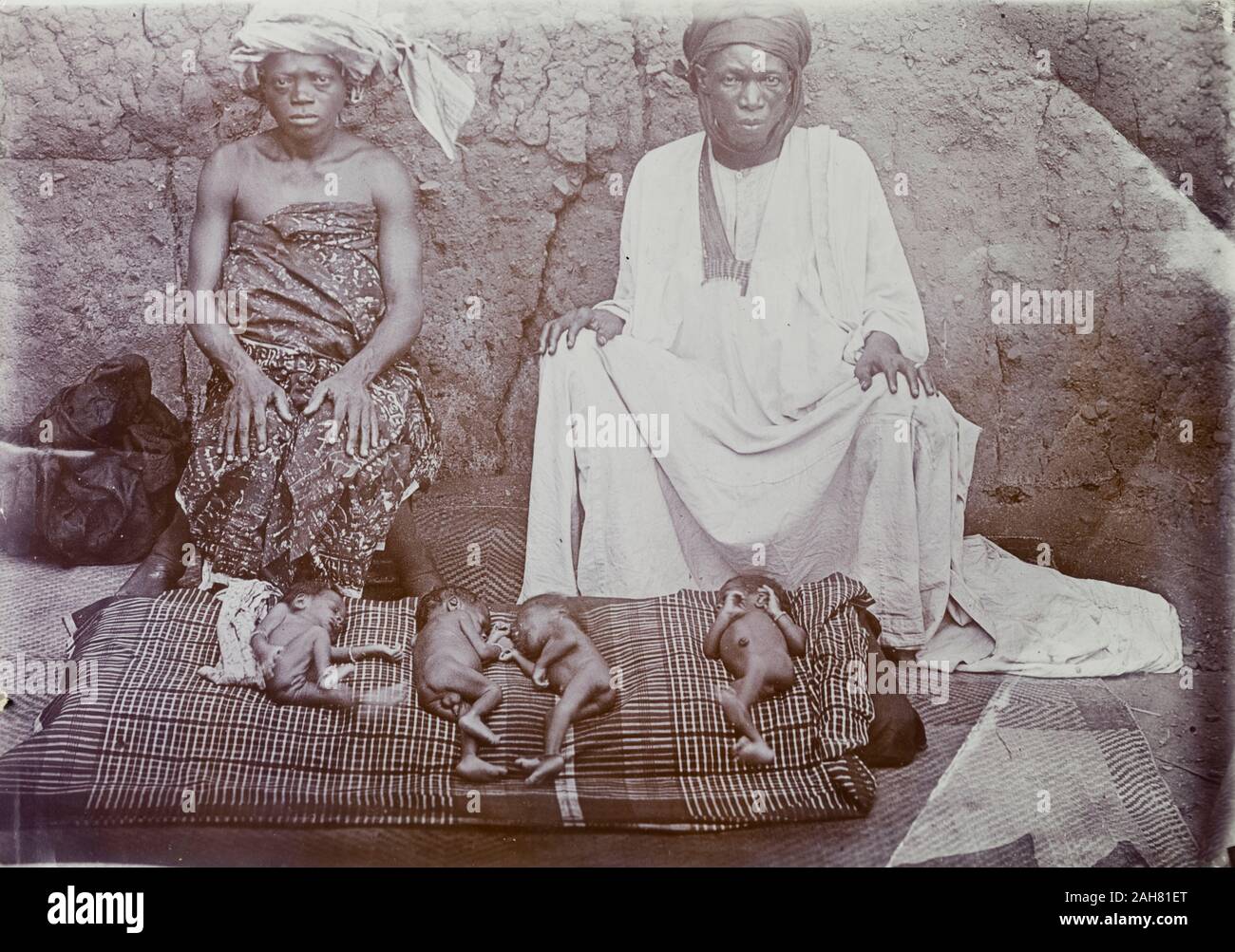 La Nigeria, giovane seduto con il loro bambino gemelle su un tappetino di fronte a loro, [c.1920s]. 2000/098/2/96. Foto Stock