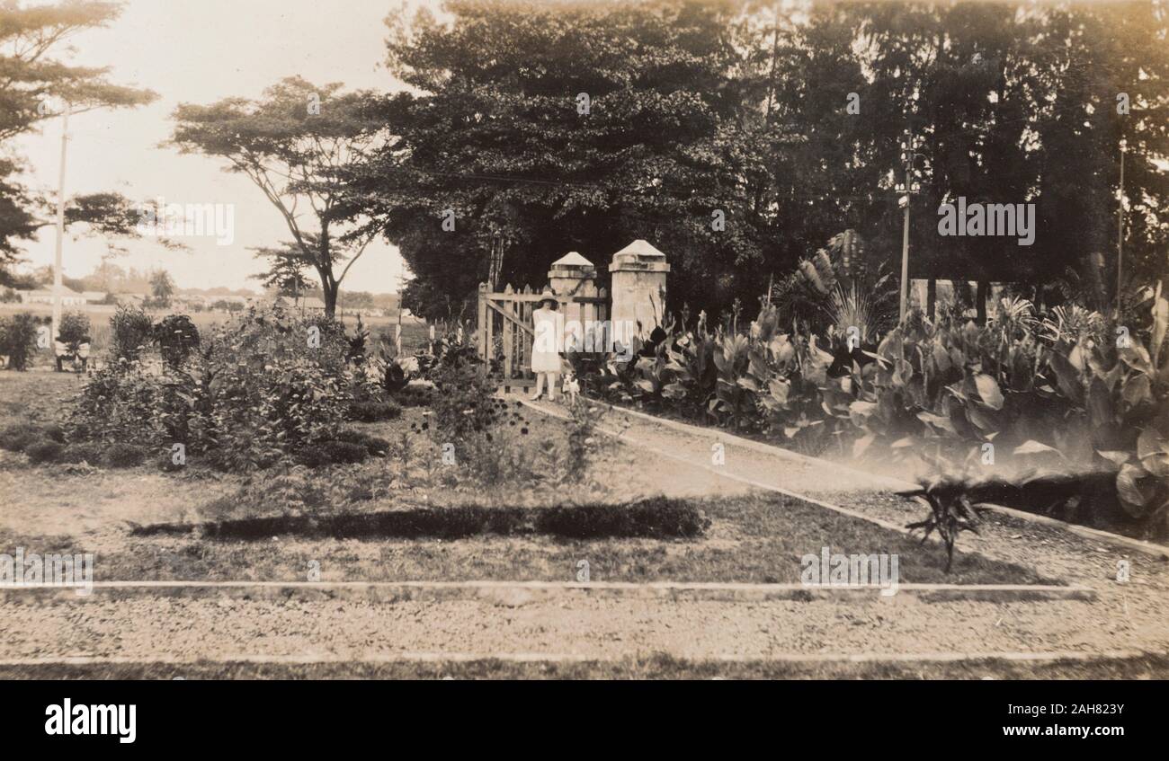 La Nigeria, la didascalia recita: "Club Lagos Giardini 1928'. Una donna europea in un vestito e cappello per il sole sorge su un sentiero all'ingresso del Club Lagos giardini, 1928. 2000/098/1/9. Foto Stock
