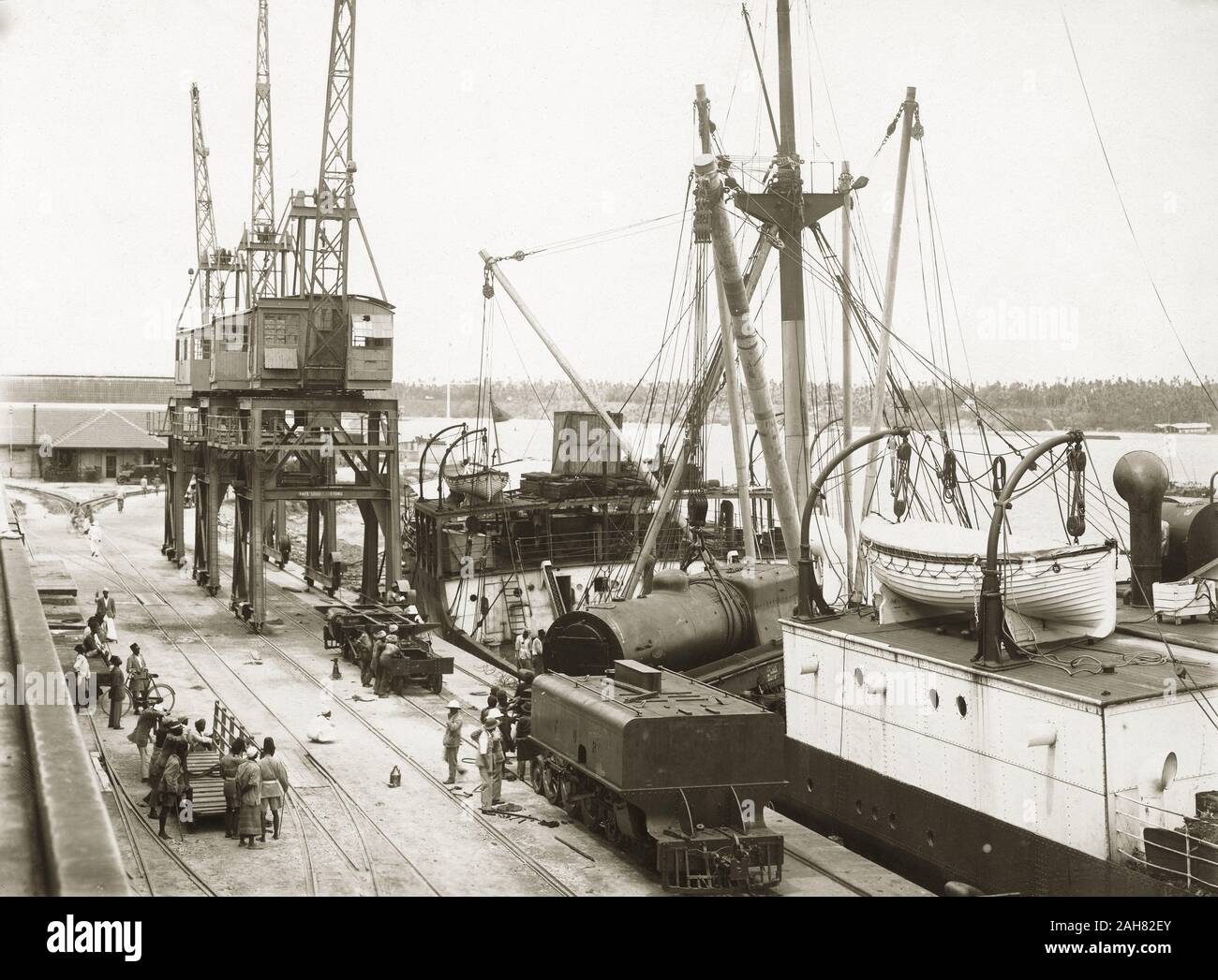 Il Kenya, una locomotiva a vapore e dei bandi di gara nel processo di essere scaricati dalla nave da carico SS Harmonides a Kilindini Harbour. Gli operai sono in piedi vicino a. Parte di una serie che mostra la locomotiva di scarico, [1920]. 1999/135/1/1/2. Foto Stock