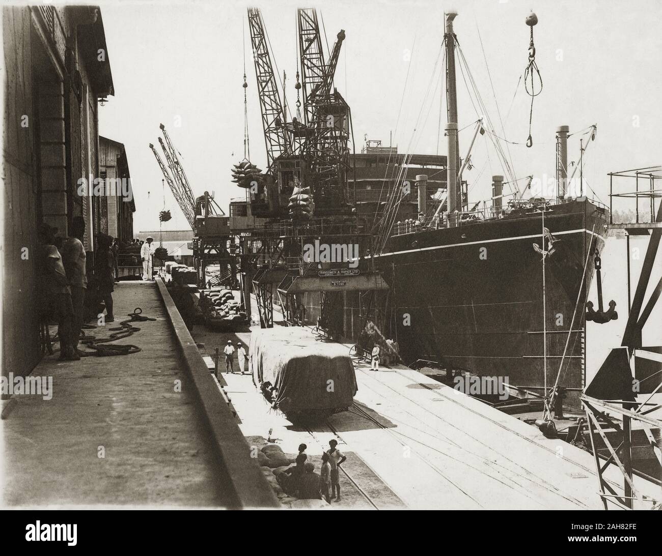 Kenya, vista dall'estremità di prua del SS Modasa mostra borse di carico che viene scaricata in corrispondenza di Kilindini Harbour. Gli operai sono in piedi vicino a. , [1920]. 1999/135/1/1/7. Foto Stock