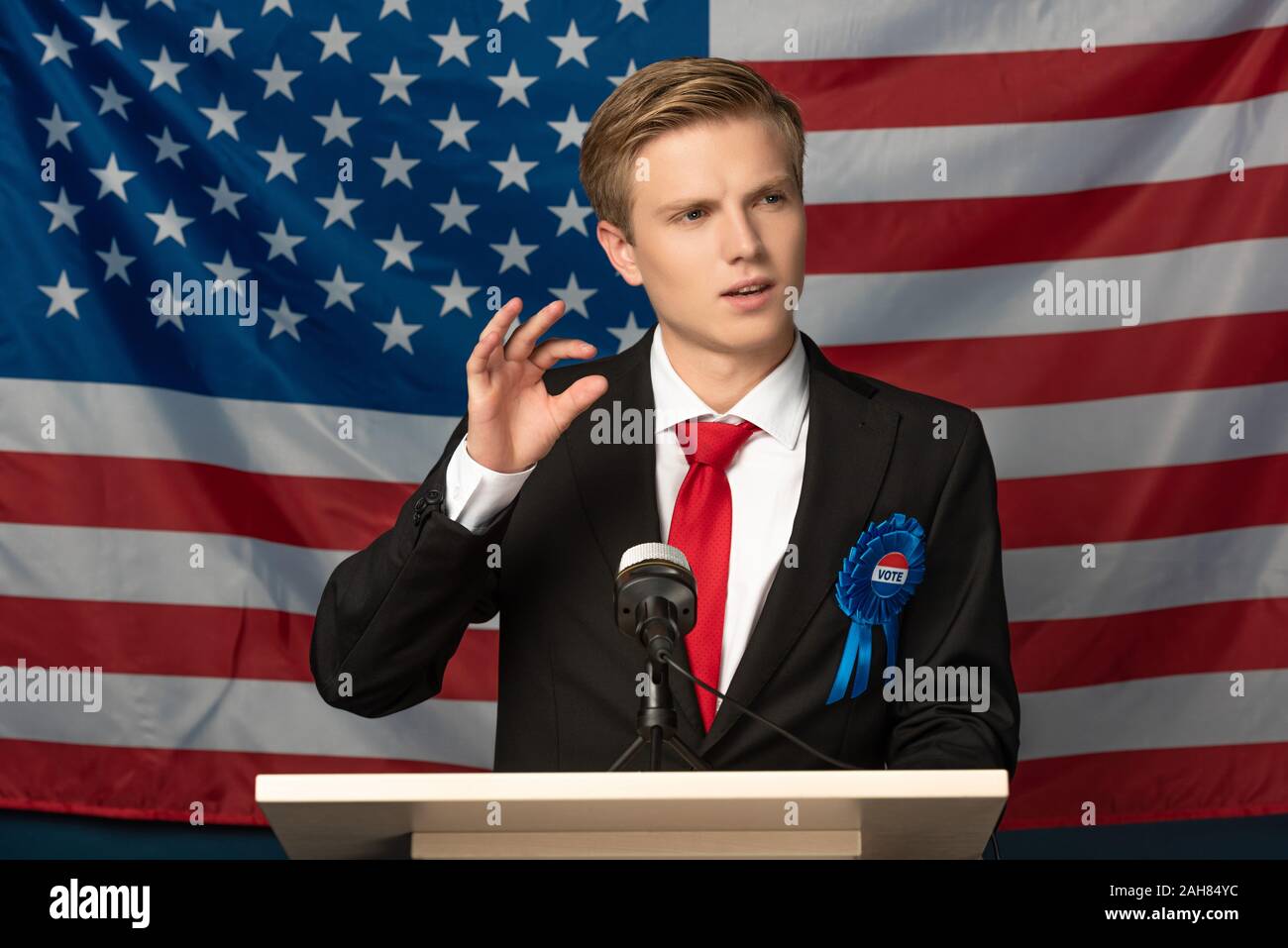 Kiev, Ucraina - 18 ottobre 2019: emotional man imitando Donald Trump sulle tribune durante il discorso sulla bandiera americana sfondo Foto Stock