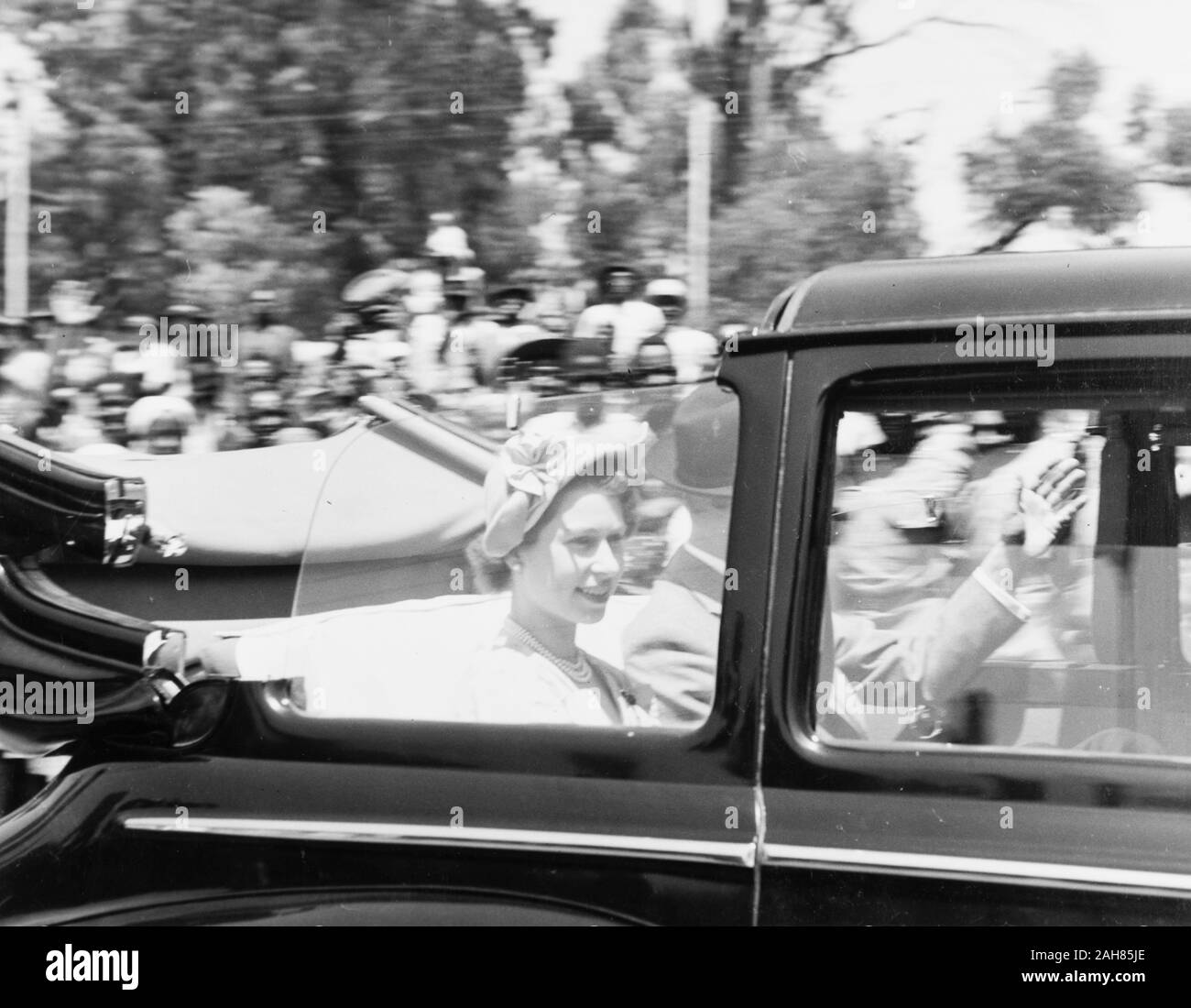 Il Kenya, una sommità aperta velocità auto passato la telecamera che trasportano la principessa Elisabetta e il Duca di Edimburgo a Nairobi municipio della città. Il Duca di Edimburgo è parzialmente oscurata dalla finestra della vettura ma può essere visto sventolare la sua mano sinistra. La Principessa Elisabetta è visto sorridere alla folla di gente che fiancheggiano la strada, febbraio 1952. 2001/090/1/4/1/57. Foto Stock