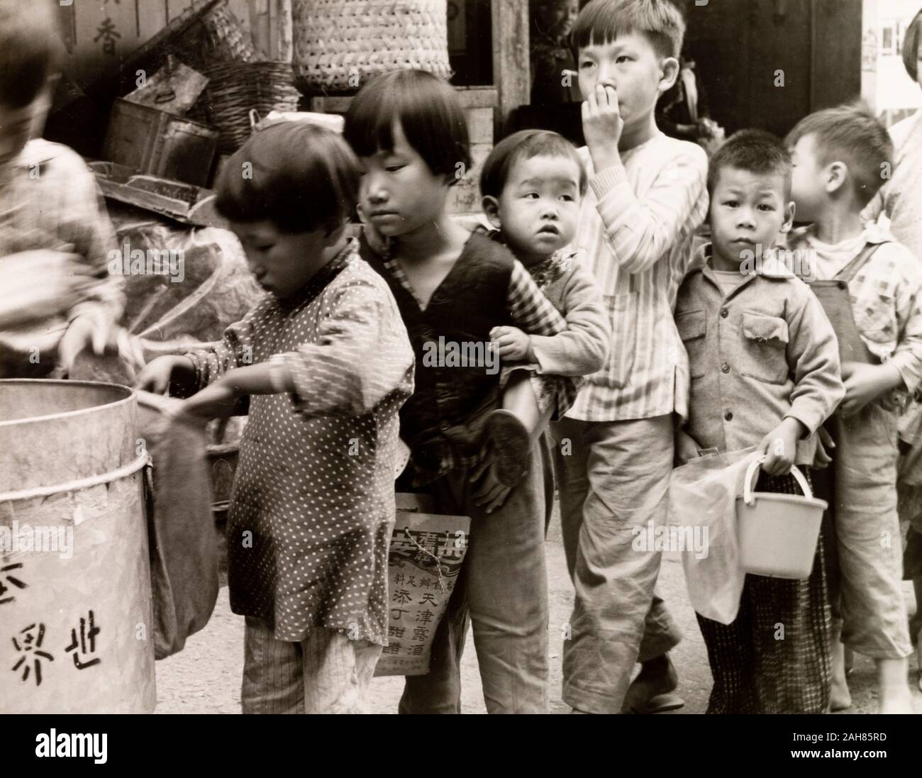 Hong Kong, bambini in coda per il cibo, Hong KongCity bambini coda con contenitori, in attesa di ricevere le razioni di cibo da una organizzazione senza scopo di lucro. Manoscritto originale didascalia: scolari che ricevono regali di cibo da una organizzazione di beneficenza, 1963. 2005/010/1/11/41. Foto Stock