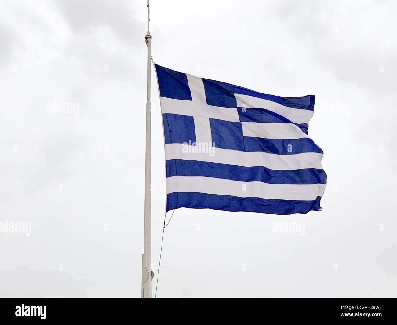 La bandiera nazionale della Grecia è sventolata su un albero nel vento. Chiamato anche il cielo blu e bianco. Pezzo di tessuto e un banner, utilizzato come simbolo patriottico. Foto Stock