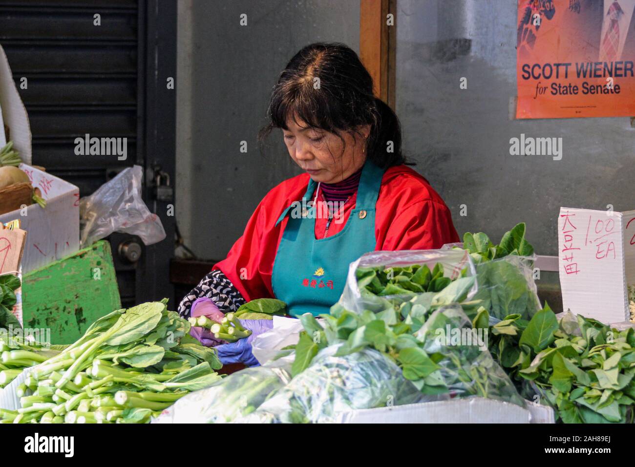 Di mezza età strada femmina venditore a vendere verdure in San Francisco Chinatown, Stati Uniti d'America Foto Stock