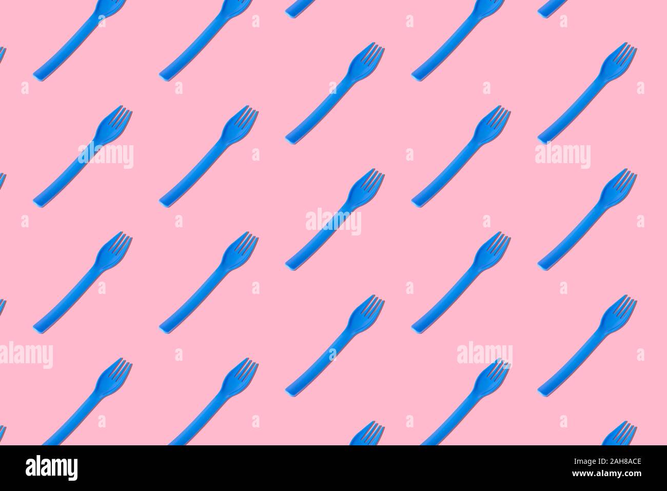 Lay piatto di plastica blu forche pattern sul rosa pastello background creativo minima nozione di cibo. Foto Stock