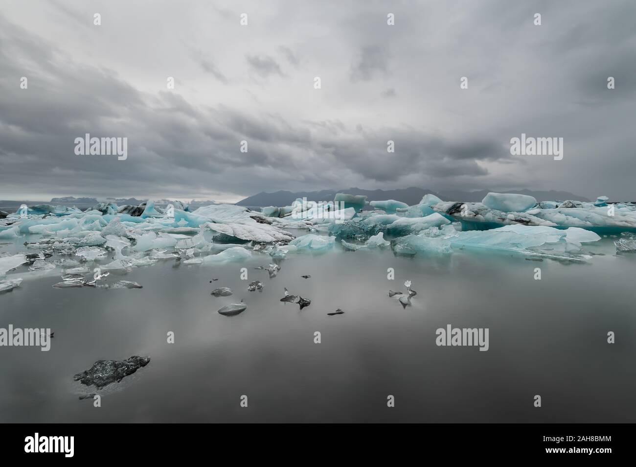 Ampia vista della laguna islandese dell'iceberg, con un certo numero di iceberg che galleggiano in primo piano e un ghiacciaio distante sullo sfondo Foto Stock