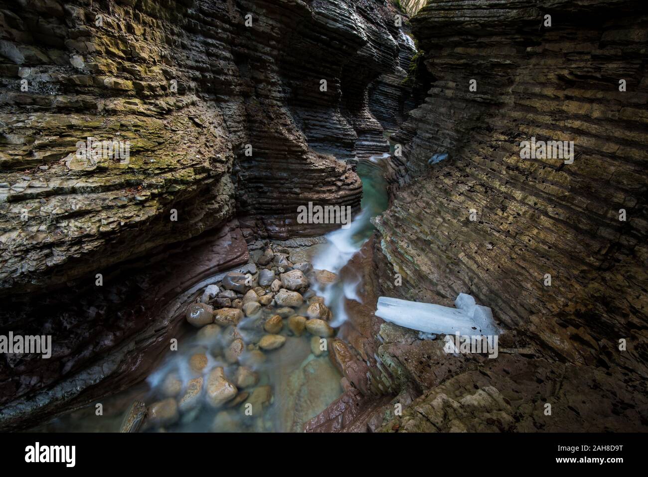Ampia vista angolare dell'interno di un canyon in arenaria rossa con un ruscello che scorre sul fondo Foto Stock