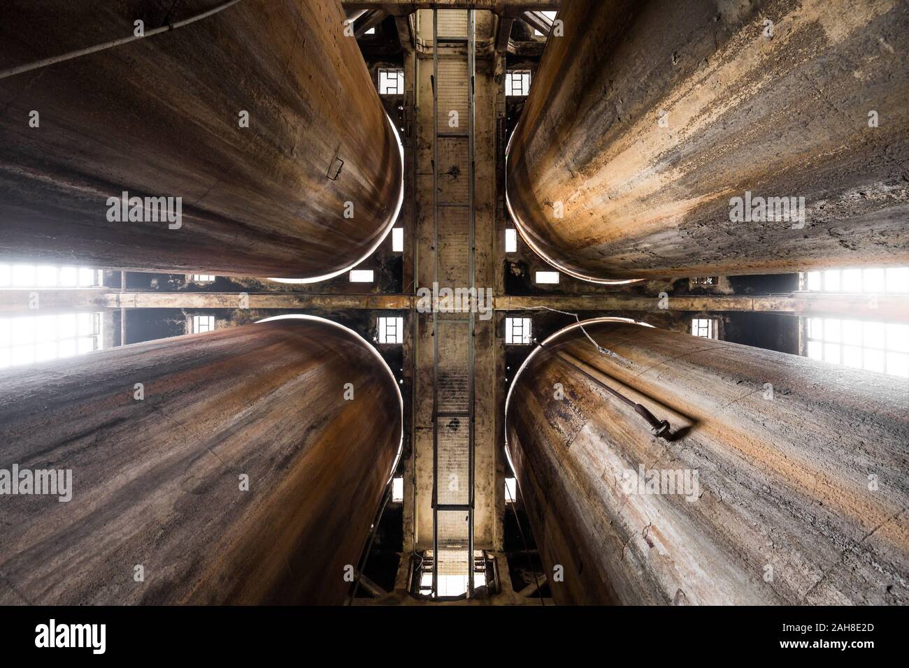 Vista grandangolare simmetrica di quattro vecchi e arrugginiti silos industriali sparati dal basso Foto Stock