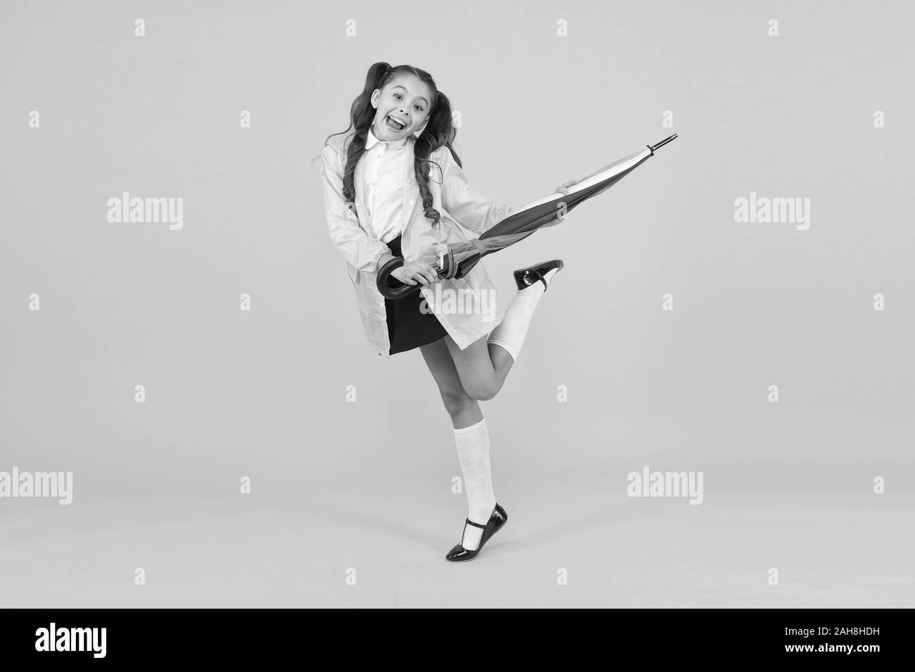 Schoolgirl elegante ragazzino con ombrellone usura impermeabile impermeabile. Resistente all'acqua di vestiti. La pioggia d'autunno. Andare a scuola. Abbigliamento antipioggia. La pioggia è finito. La pioggia caduta. In attesa di giorni di pioggia. Foto Stock