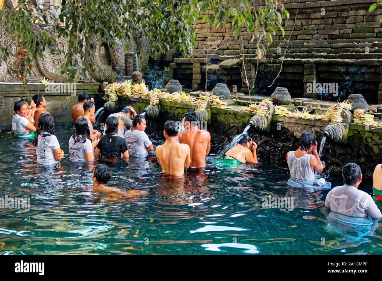 Gruppo di persone in attesa in una que a teste di doccia in primavera sacra acqua in piscina sacra nella Tirta Empul Temple, Bali Foto Stock