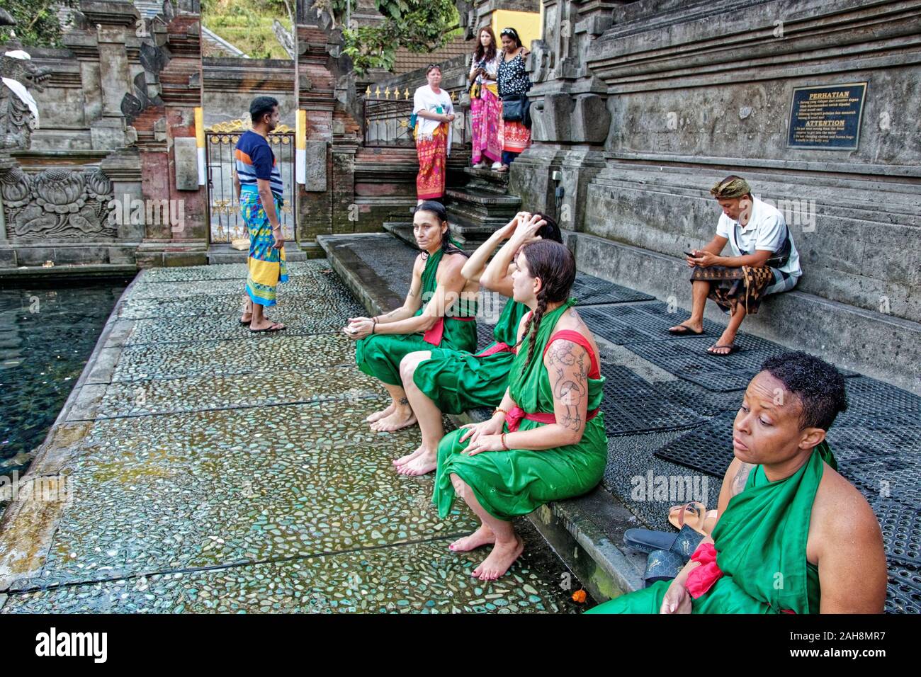 Le donne in tessuto verde vestiti seduta sul bordo della piscina sacra mi Tirta Empul Temple di Bali Foto Stock