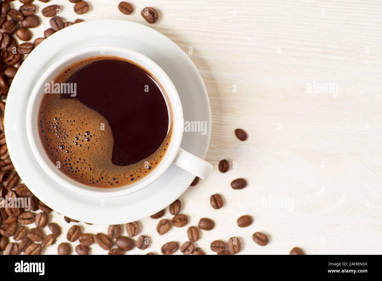 Americano e i chicchi di caffè in bianco sullo sfondo di legno Foto Stock