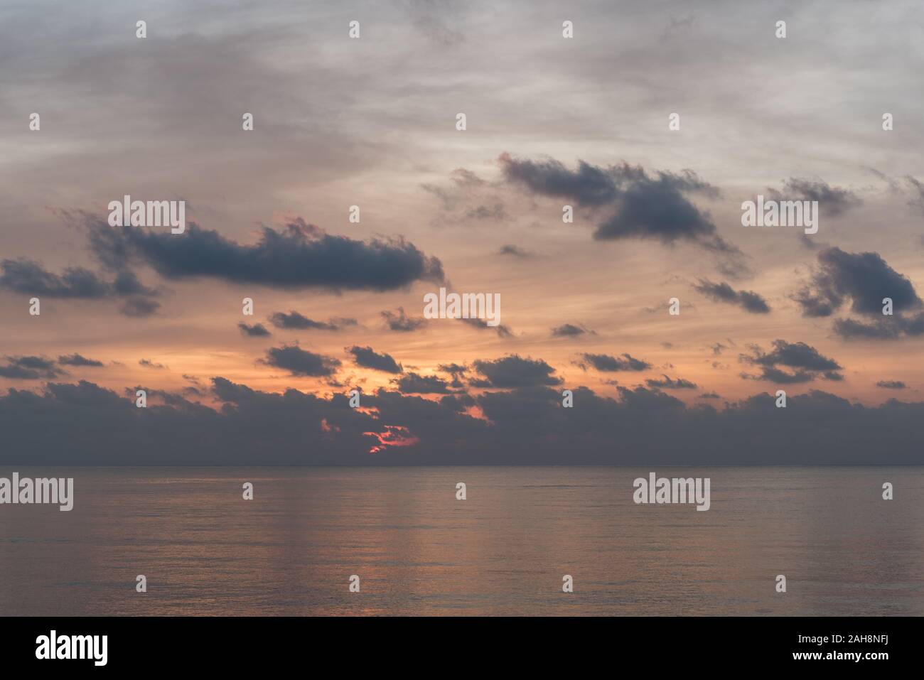 Alba sul mare orizzonte con ancora seawaters, nuvole scure e gioco arancione nel cielo. La mattina presto sul Golfo di Thailandia in Prachuap Khiri Khan Foto Stock