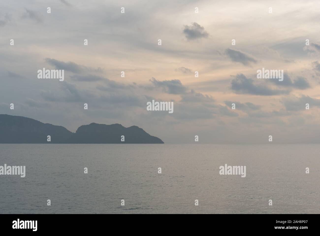 La mattina presto vista mare: spindrift nuvole, acque ferme e una lontana terra montana (una penisola cape) all'orizzonte in Prachuap Khiri Khan, Thailandia. Foto Stock