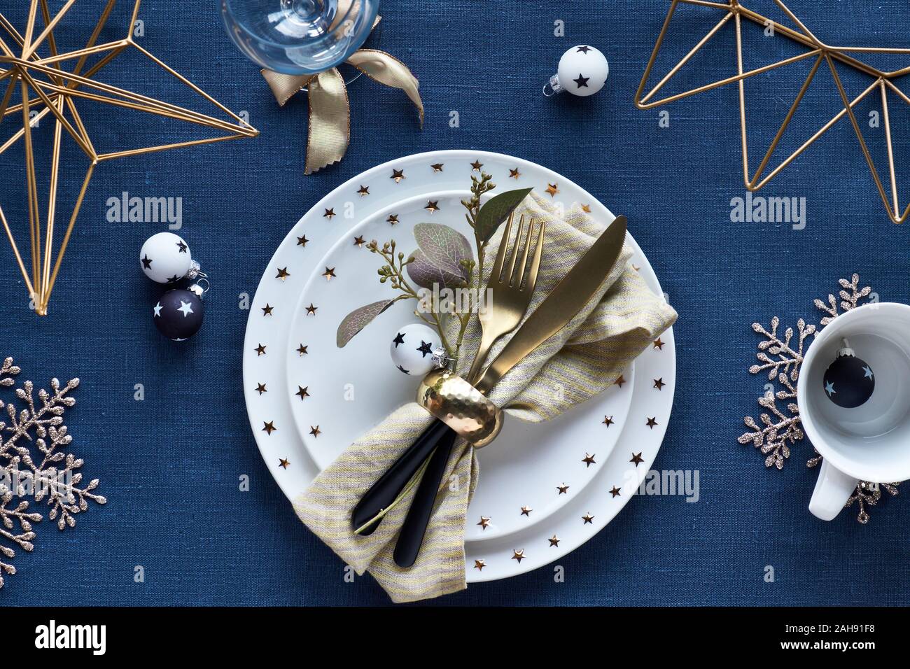 Tavola di Natale la configurazione con piastra bianca e dorata utensili e decorazioni dorate. Bianco e nero ciondoli di vetro con le stelle. Appartamento laico, vista dall'alto su da Foto Stock