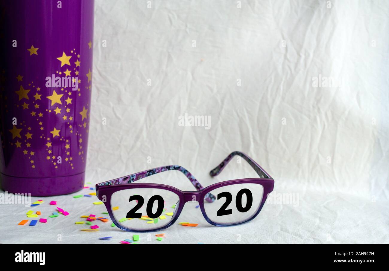 Annunciando il 2020 sia in visione e un nuovo anno con un party concetto comprendente una coppa di porpora, stelle, coriandoli, copia dello spazio e bokeh effetto. Foto Stock