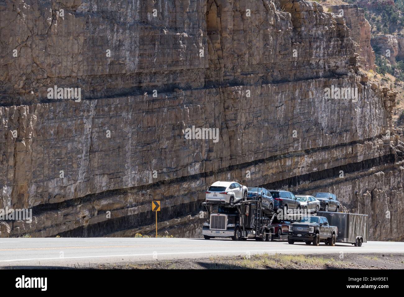 I carrelli di guida attraverso una strada tagliata con cuciture di carbone sulla Highway 6 in carbonio County, Utah. Foto Stock