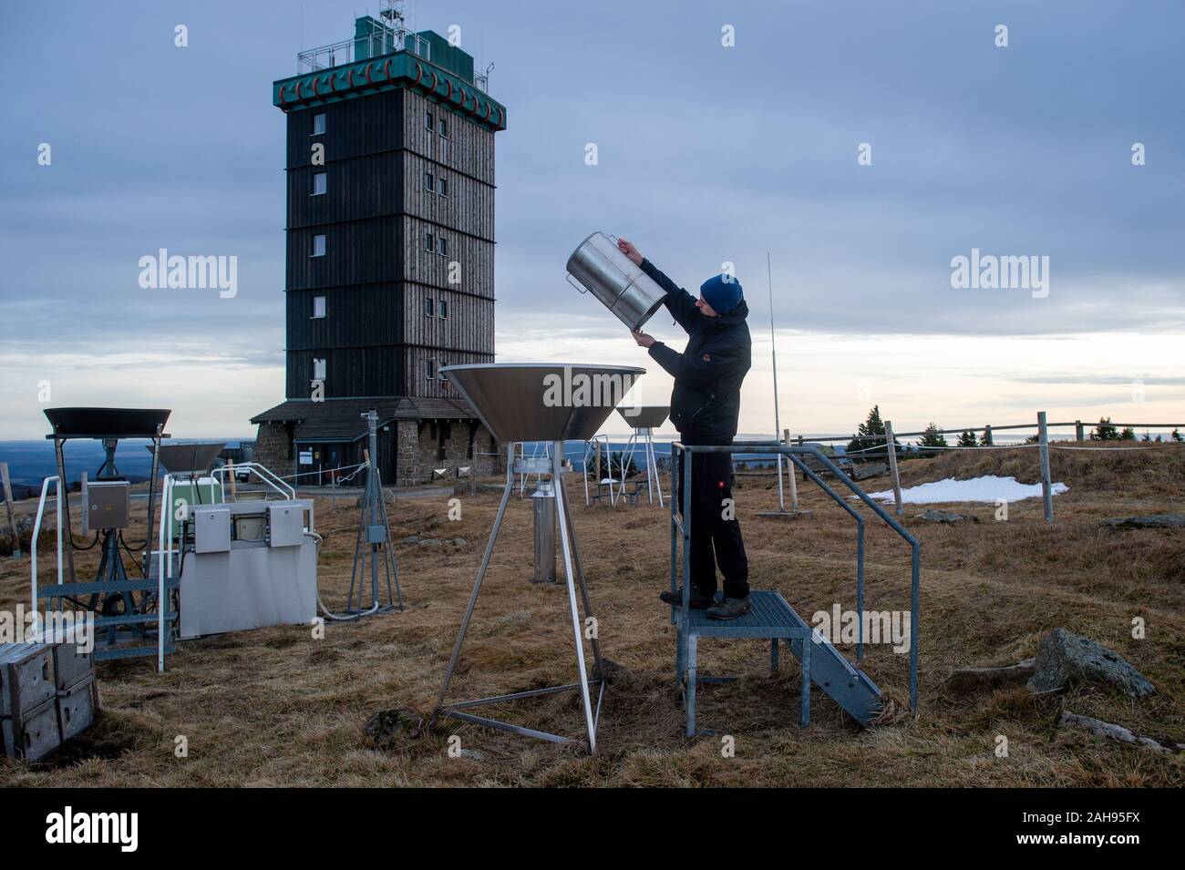 19 dicembre 2019, Sassonia-Anhalt, Wernigerode: Marc Kinkeldey, osservatore meteorologico tedesco del servizio meteo (DWD) il controllo manuale di una stazione di misurazione sul Brocken per determinare la quantità di pioggia. Sulla sinistra è possibile vedere l'Automated stazione di misurazione per la pioggia. Per 180 anni il Brocken era un posto di lavoro estreme per meteo osservatori. A partire dal 1 o gennaio 2020, automatico tecnologia di misurazione assumerà. Come su altri vertici come il massiccio dello Zugspitze e il Fichtelberg, il tedesco servizio meteo è ora interrompendo il lavoro degli osservatori meteo sul più alto vertice di Harz. Il prossimo anno, solo la radioattività w Foto Stock