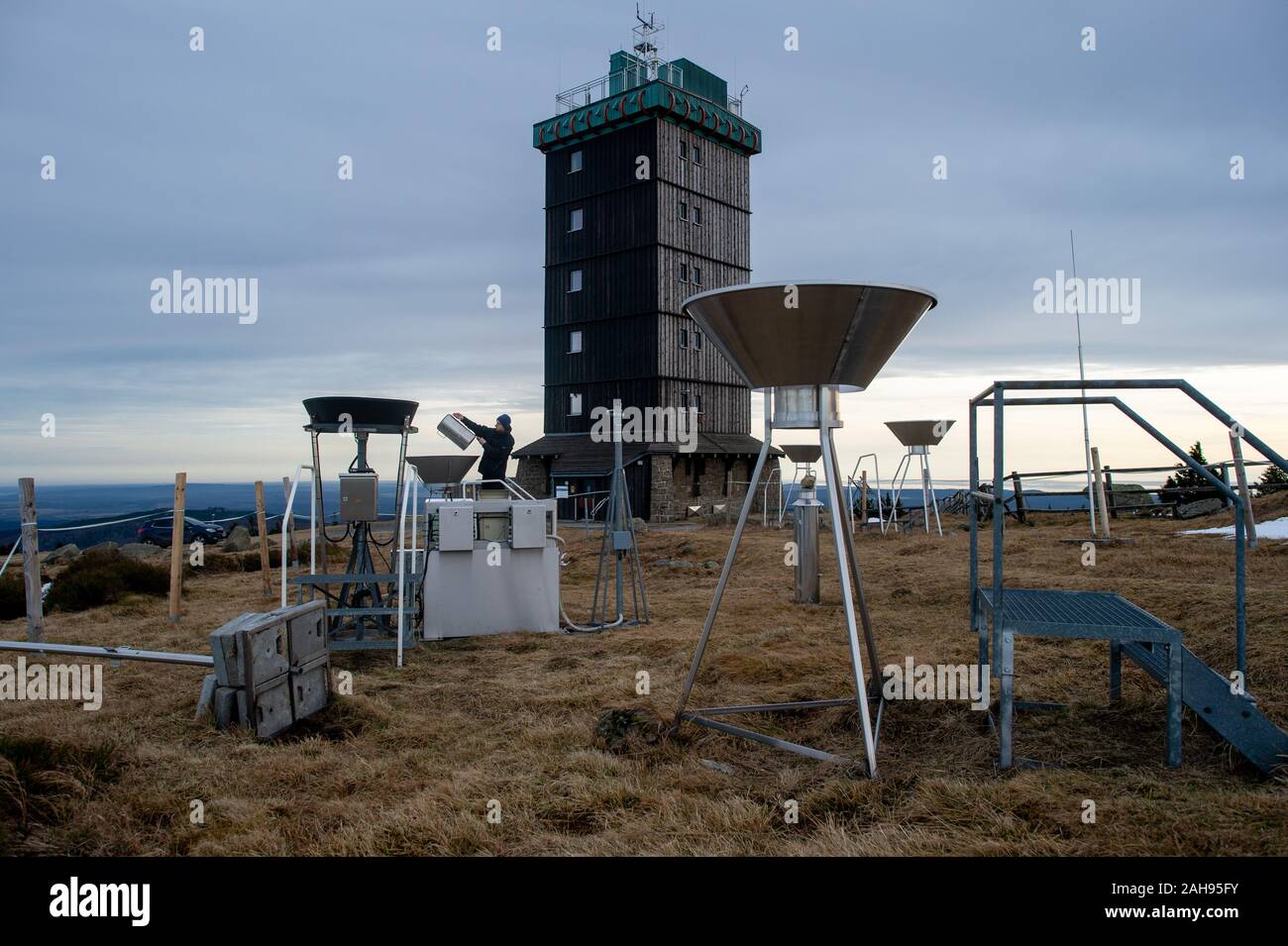 19 dicembre 2019, Sassonia-Anhalt, Wernigerode: Marc Kinkeldey, osservatore meteorologico tedesco del servizio meteo (DWD), controlli manualmente una stazione di misurazione sul Brocken per determinare la quantità di pioggia. Sulla sinistra è possibile vedere l'Automated stazione di misurazione per la pioggia. Per 180 anni il Brocken era un posto di lavoro estreme per meteo osservatori. A partire dal 1 o gennaio 2020, automatico tecnologia di misurazione assumerà. Come su altre cime come il massiccio dello Zugspitze e il Fichtelberg, il tedesco servizio meteo è ora interrompendo il lavoro degli osservatori meteo sul più alto picco di Harz. Il prossimo anno, solo della radioattività Foto Stock