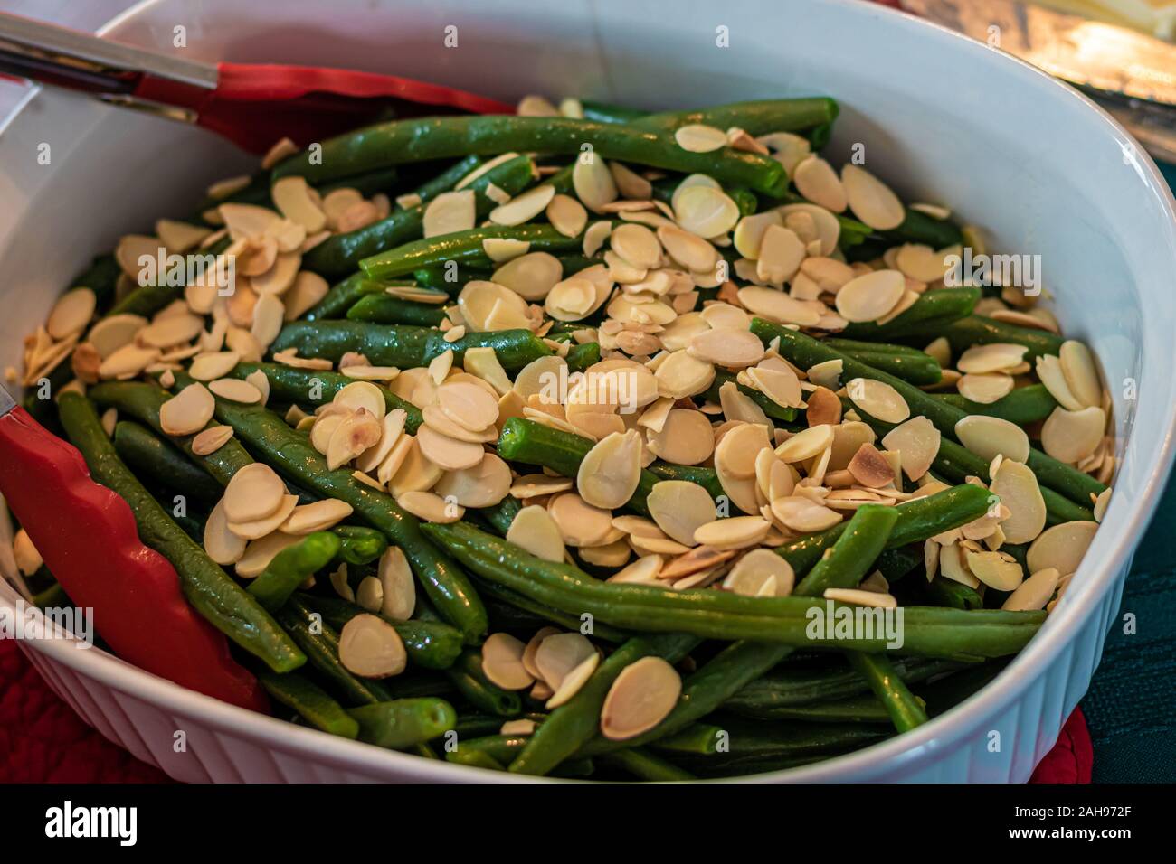 Un bianco piatto di ceramica serve un lato di fagioli verdi amandine, intendendo con una decorazione di mandorle. Il piatto è il francese fagiolini e fette di mandorle; Foto Stock