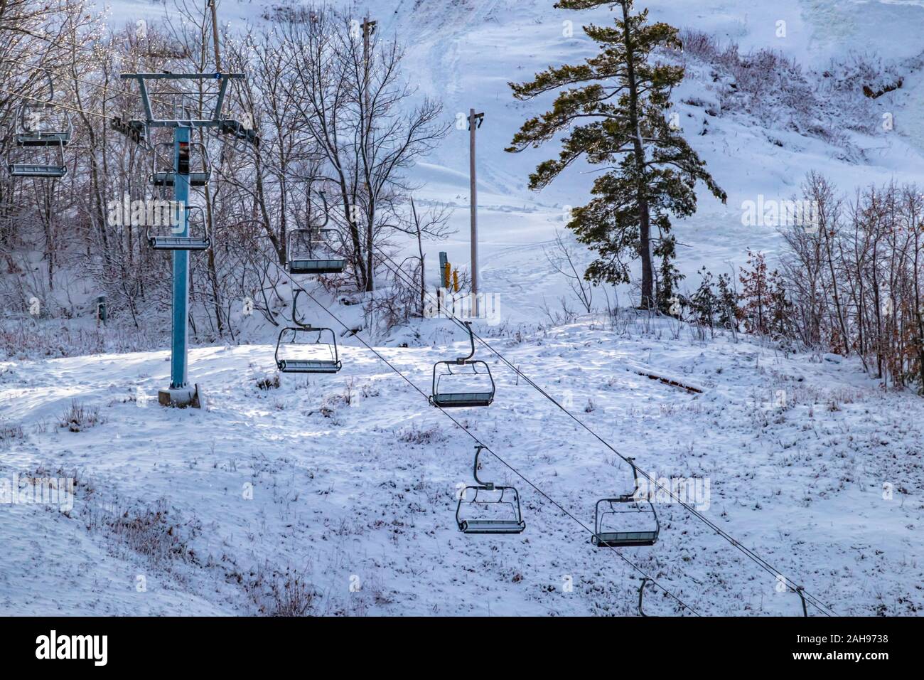 Una seggiovia è visibile sul lato di una collina di sci, le sue sedi vuote pensili e immobile come la collina è preparato per gli sciatori e gli snowboarder pronto all'uso. Foto Stock