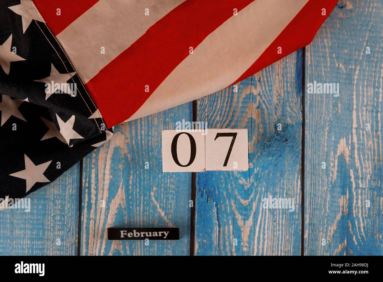 07 febbraio calendario splendidamente sventolare stelle e strisce della bandiera americana sul vecchio blu tagliere in legno. Foto Stock