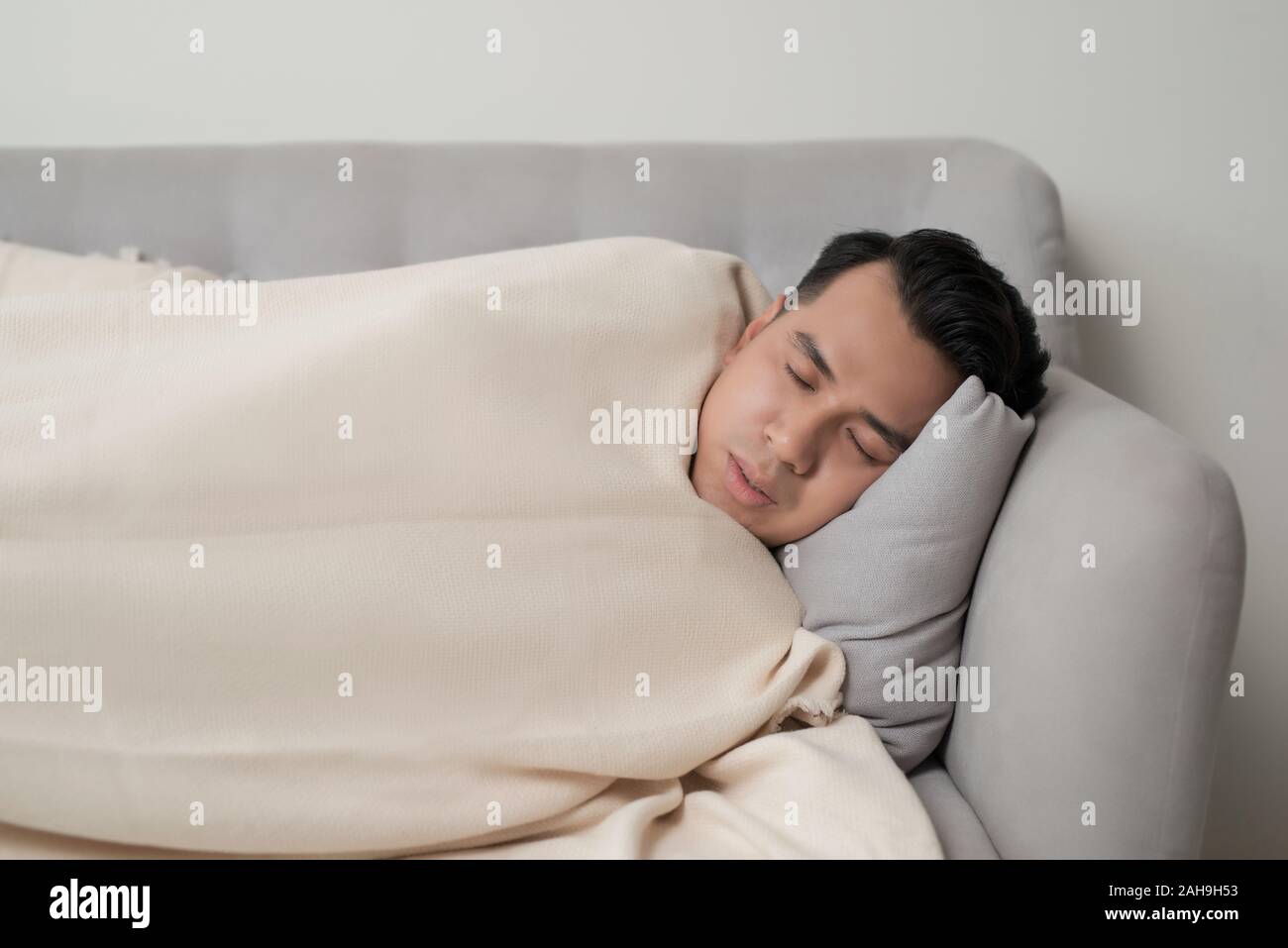 Asian eldely uomo malato sento mal di testa sdraiato sul divano di casa Foto Stock